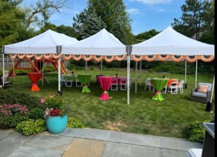 White canopy tents with pink and green tables set up on a grassy lawn for an outdoor event.