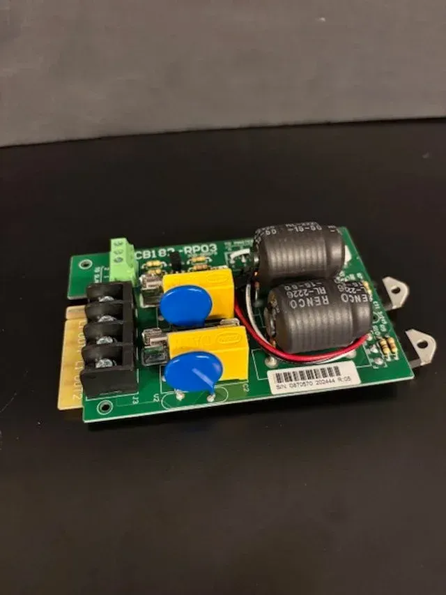 Close-up of a small electronic circuit board with capacitors, wires, and connectors on a black surface
