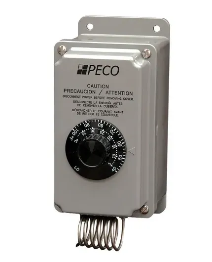 Gray PECO control box with a black dial and coiled spring on the bottom, mounted on a wall.