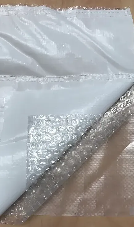 Clear plastic bubble wrap and a white padded mailing envelope on a beige surface.