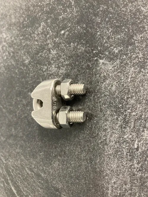 Metal wire rope clamp with two bolts on a gray textured surface.