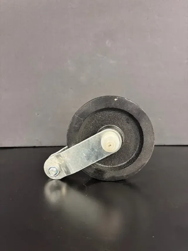 Small metal wheel assembly with an angled silver arm on a black surface against a gray background
