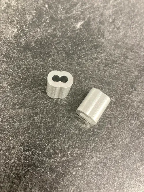 Two small silver cylindrical metal pieces on a dark textured surface