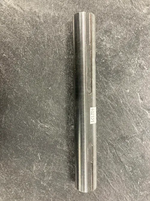 A silver metal cylinder lying vertically on a gray stone surface
