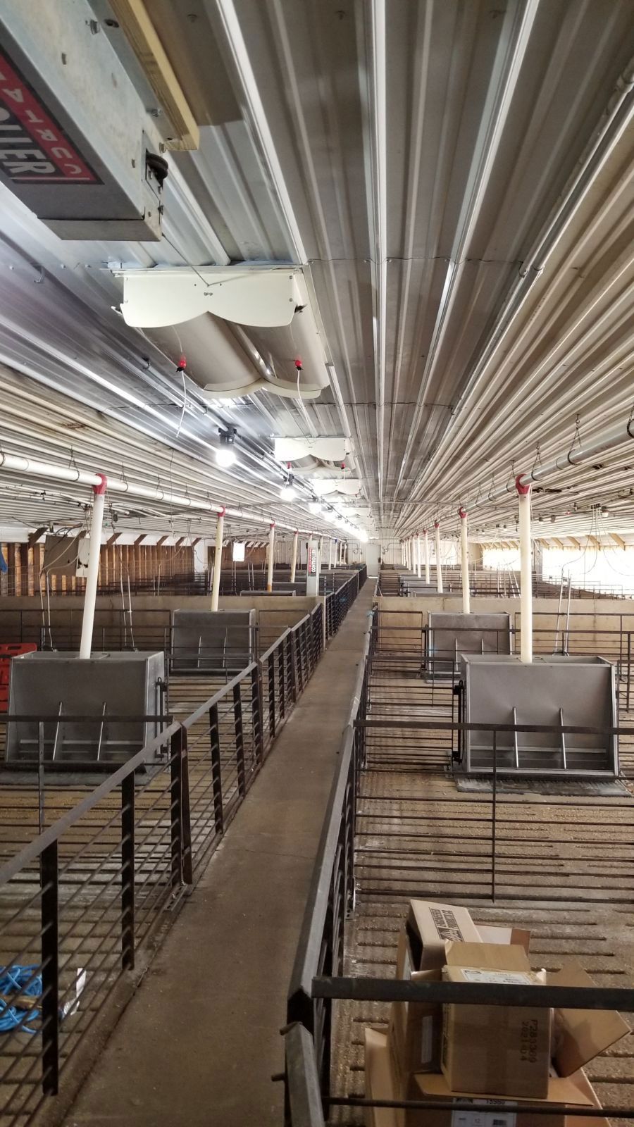 Empty industrial loft with metal railings, wooden floors, and exposed ceiling pipes.