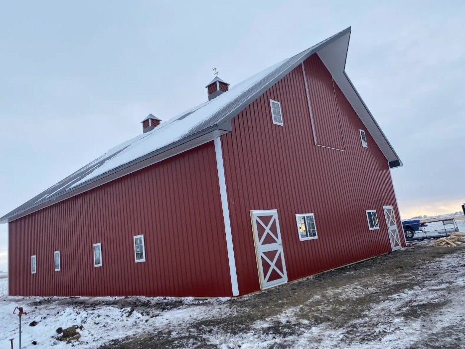 Red barn with white trim on a snowy rural landscape at dusk