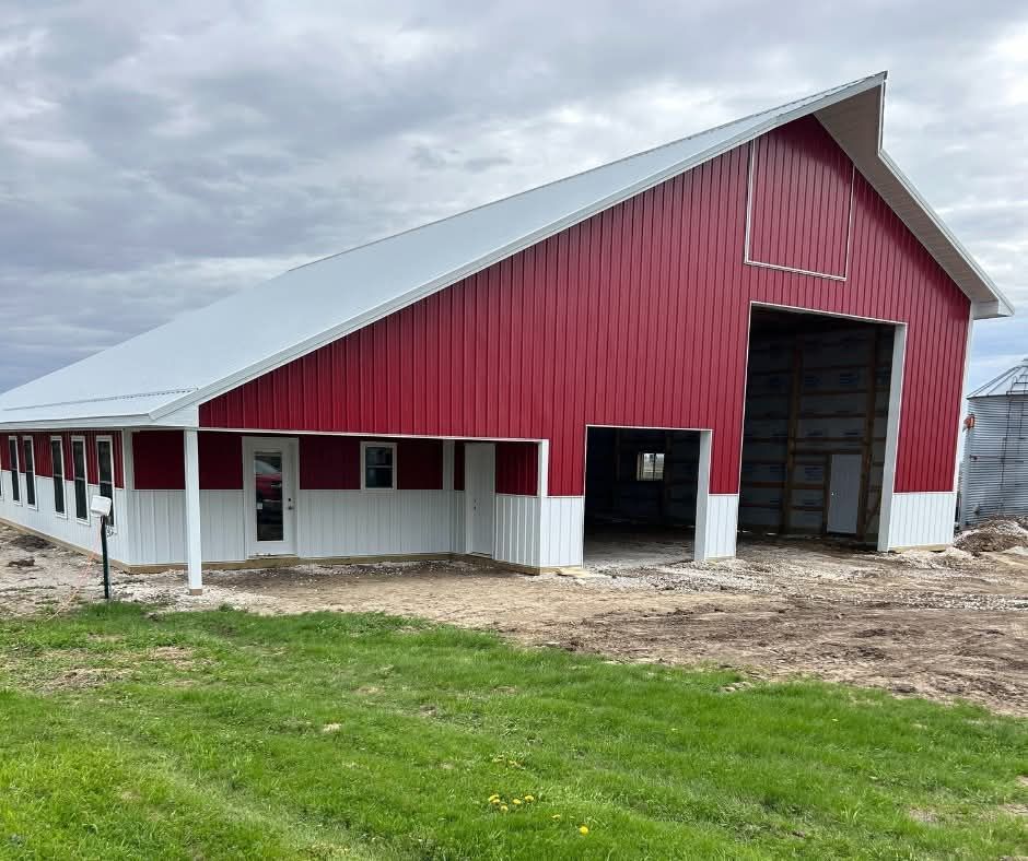 Red barn with white trim and open front door on a grassy farm lot