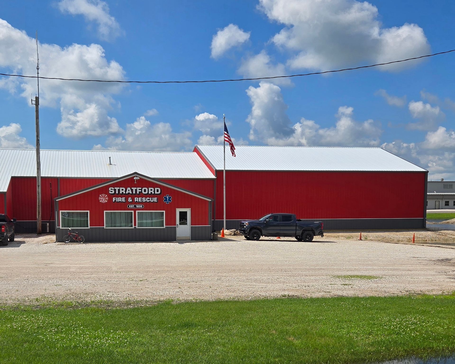 Red building with white roof and sign, black pickup parked outside under a blue sky