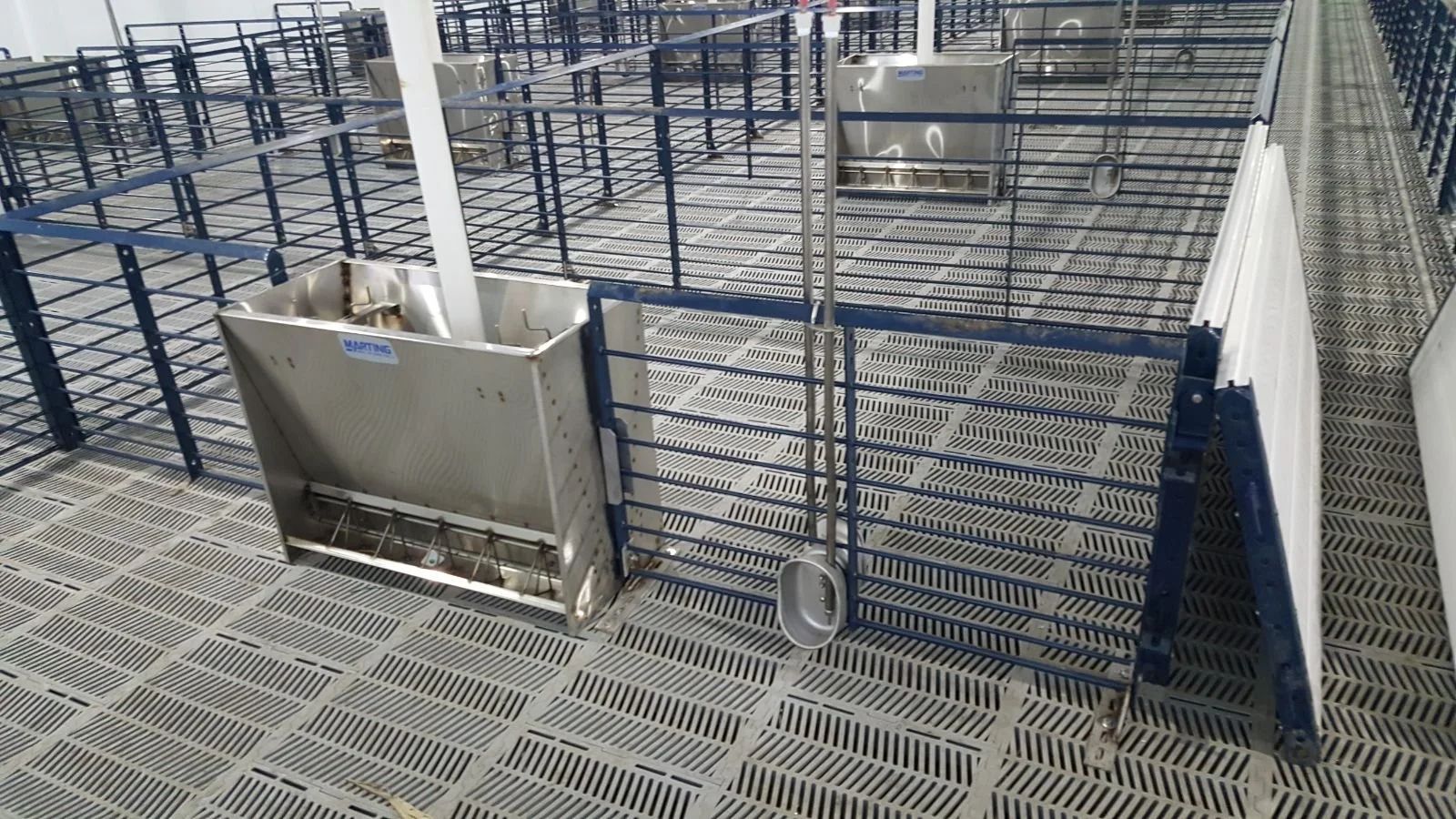 Blue metal grating walkway and railings around a large industrial tank with pipes.
