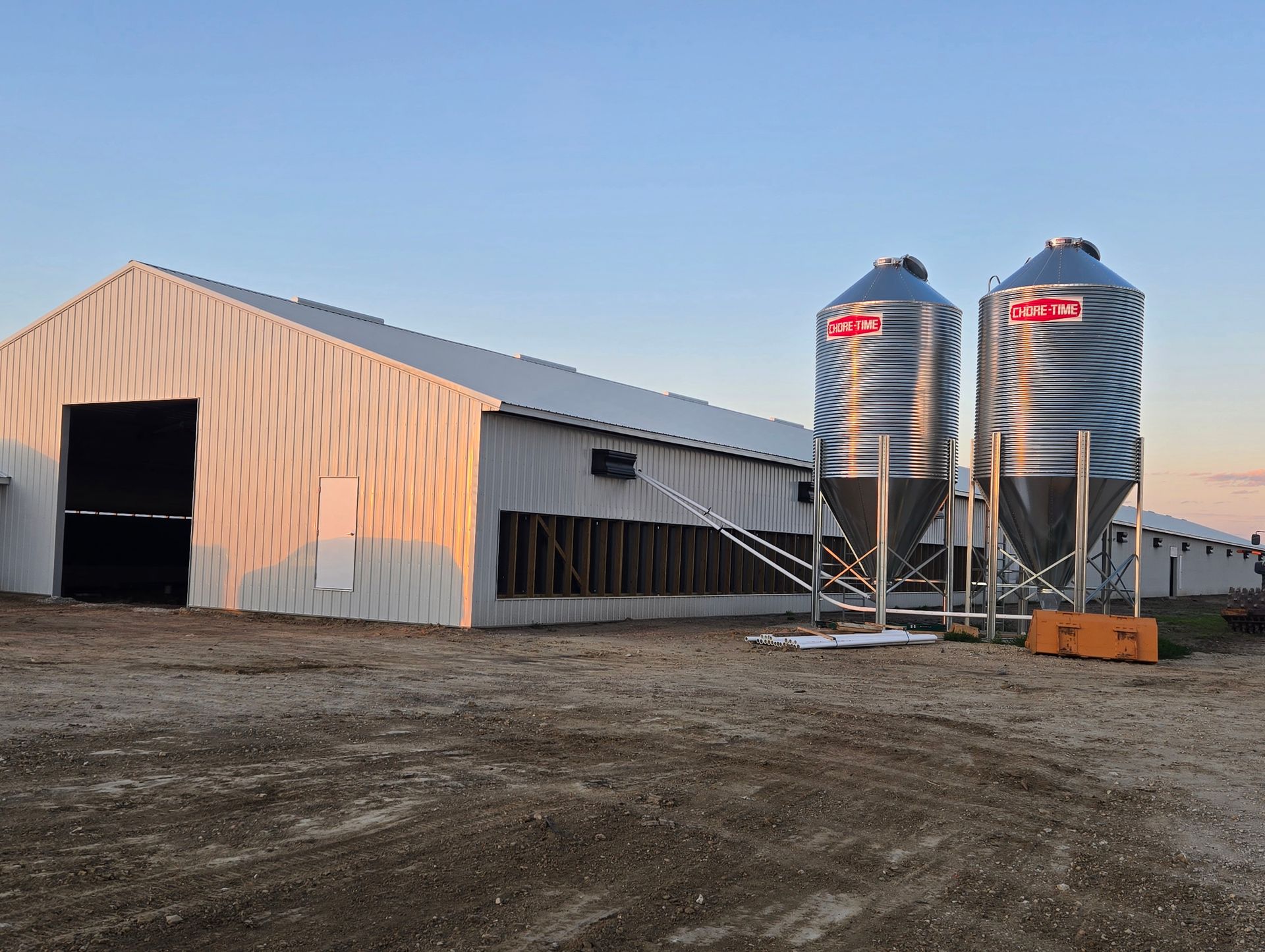 Grain silo and white storage building on a farm at sunset