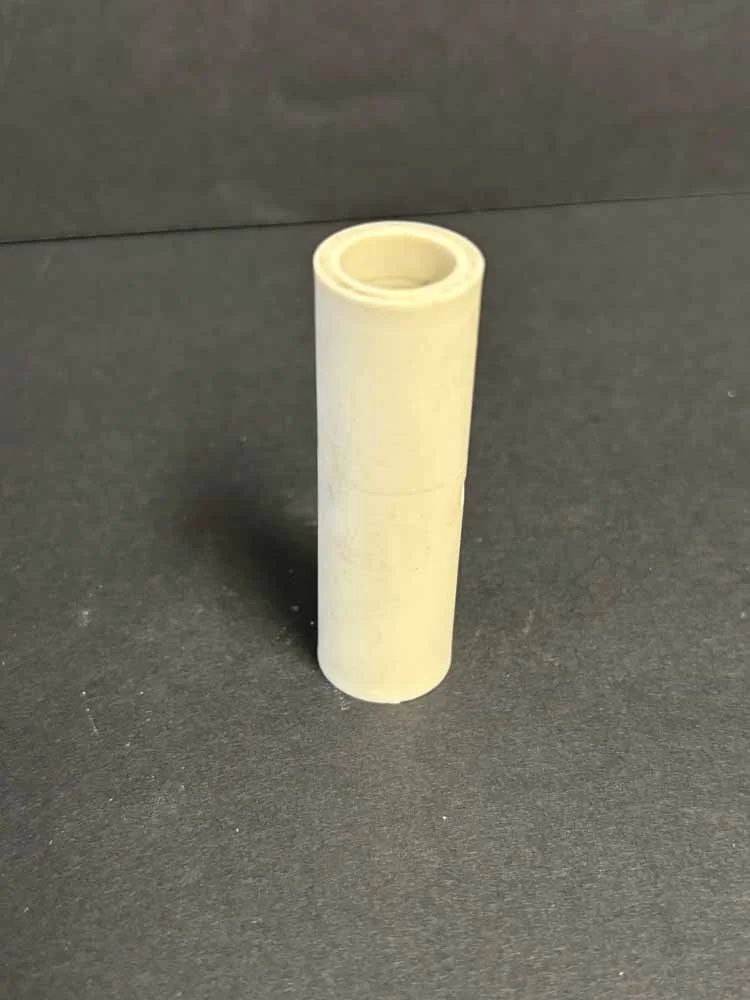 Small beige cylindrical plastic tube standing upright on a dark surface.
