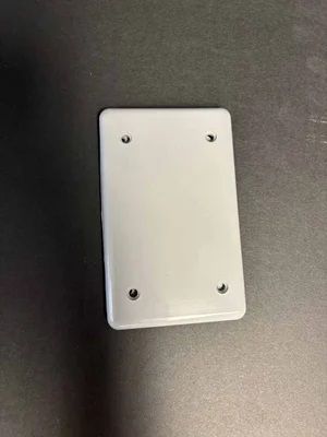 White wall plate with four screws on a dark background