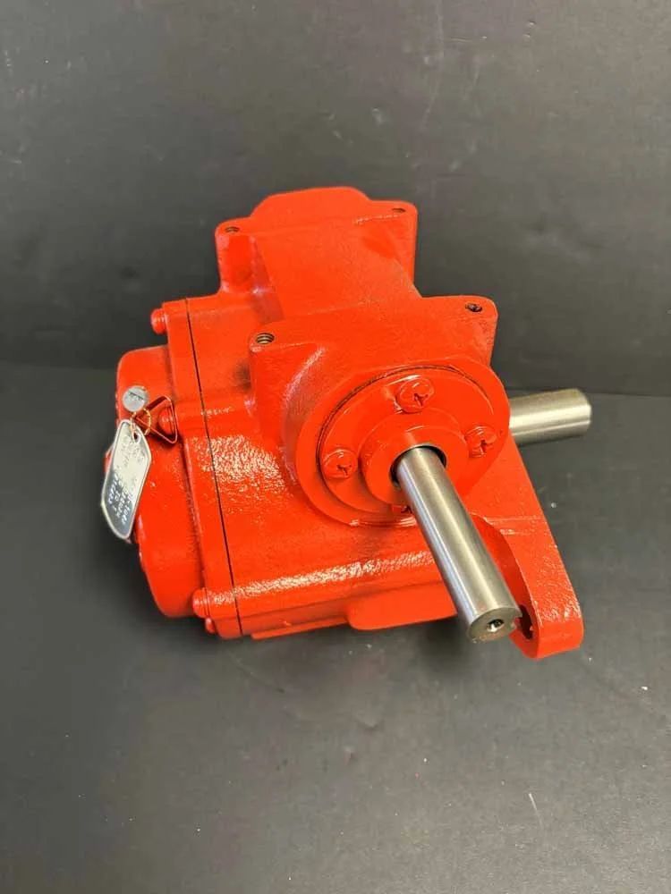 Orange industrial gearbox with two metal shafts on a dark background