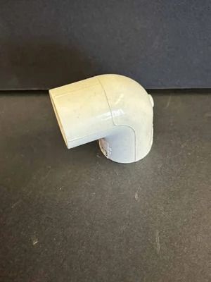 White PVC elbow pipe fitting on a dark surface