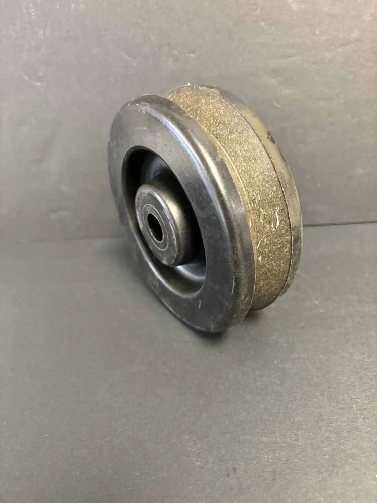 Small metal wheel or pulley with a beige abrasive outer rim on a gray background