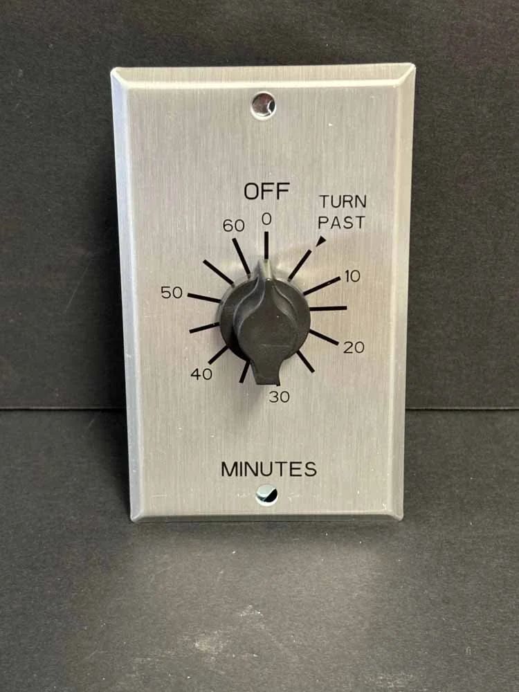 Wall-mounted beige timer switch with black knob labeled minutes and turn past off.