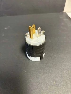 Black cylindrical electrical connector with three metal prongs on a gray surface