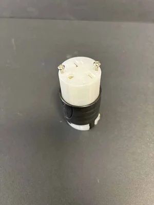 Small black-and-white cylindrical device with screws on top, standing on a gray surface.