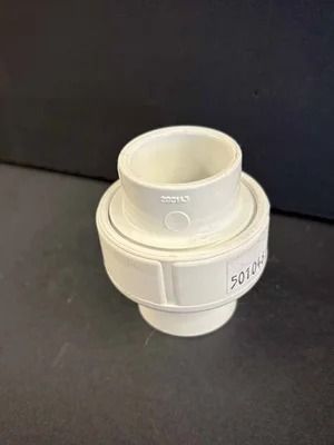 White plastic pipe fitting or connector on a dark background