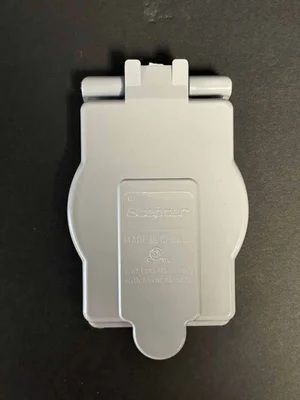 White plastic clip-on device on a dark background, with a hinge at the top and rounded tab at the bottom