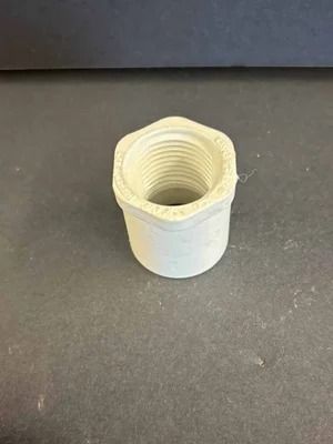 White threaded plastic pipe fitting on a dark surface