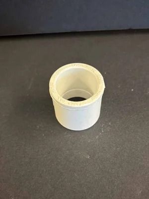 White plastic cylindrical cap on a dark surface, viewed from above.