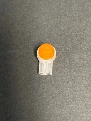 Small orange-and-white plastic clip on a dark gray surface