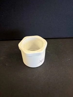 White plastic cup or small container on a dark surface against a dark background
