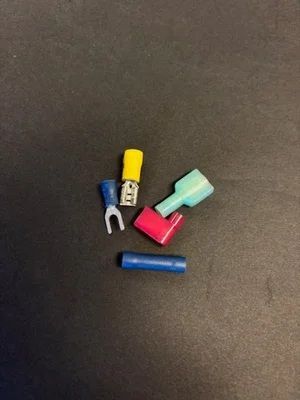 Small colorful electrical wire connectors on a dark surface.