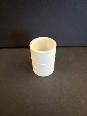 Small white plastic cup on a dark tabletop against a dark background.