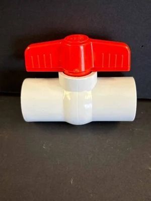 White PVC ball valve with a red handle on a dark background