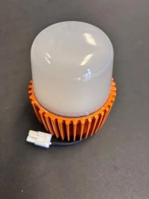 Orange heatsink with translucent white dome and small white connector on a gray surface
