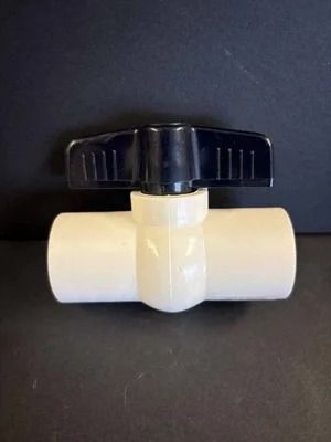 White PVC ball valve with a black handle on a dark background