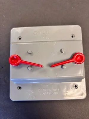 Red plastic emergency stop pull handles on a gray wall-mounted control panel
