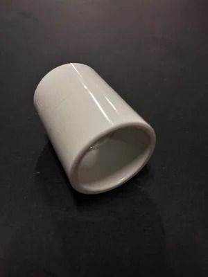 White ceramic cup lying on its side on a dark surface