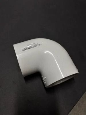 White PVC elbow pipe fitting on a dark background
