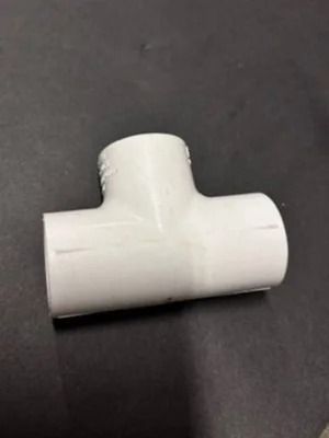 White plastic T-shaped pipe fitting on a dark surface
