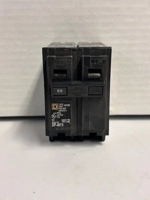 Black electrical circuit breaker mounted against a light wall.
