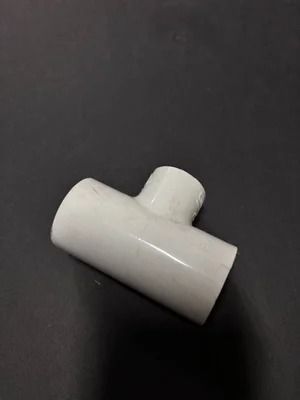 White plastic T-shaped pipe connector on a dark background