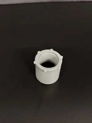 Small white plastic threaded sleeve on a dark surface