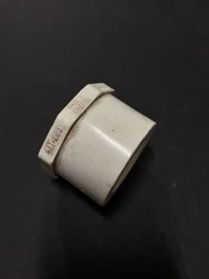 White plastic pipe fitting with a hexagonal nut on a dark background
