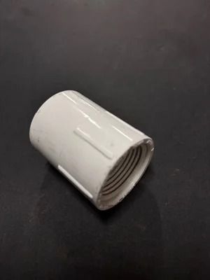 White threaded pipe coupling on a dark surface