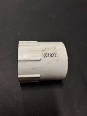 Small white cylindrical plastic part with a black printed number on a dark surface