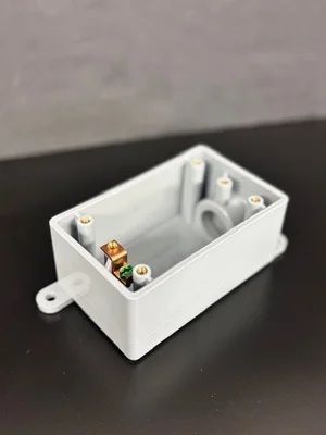 White plastic electronics enclosure with a circuit board inside on a dark surface