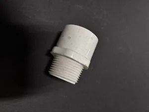 White threaded plastic pipe fitting on a dark background