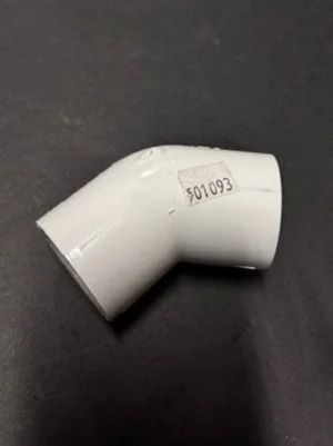 White PVC elbow pipe fitting on a dark surface, marked with the number 501093.