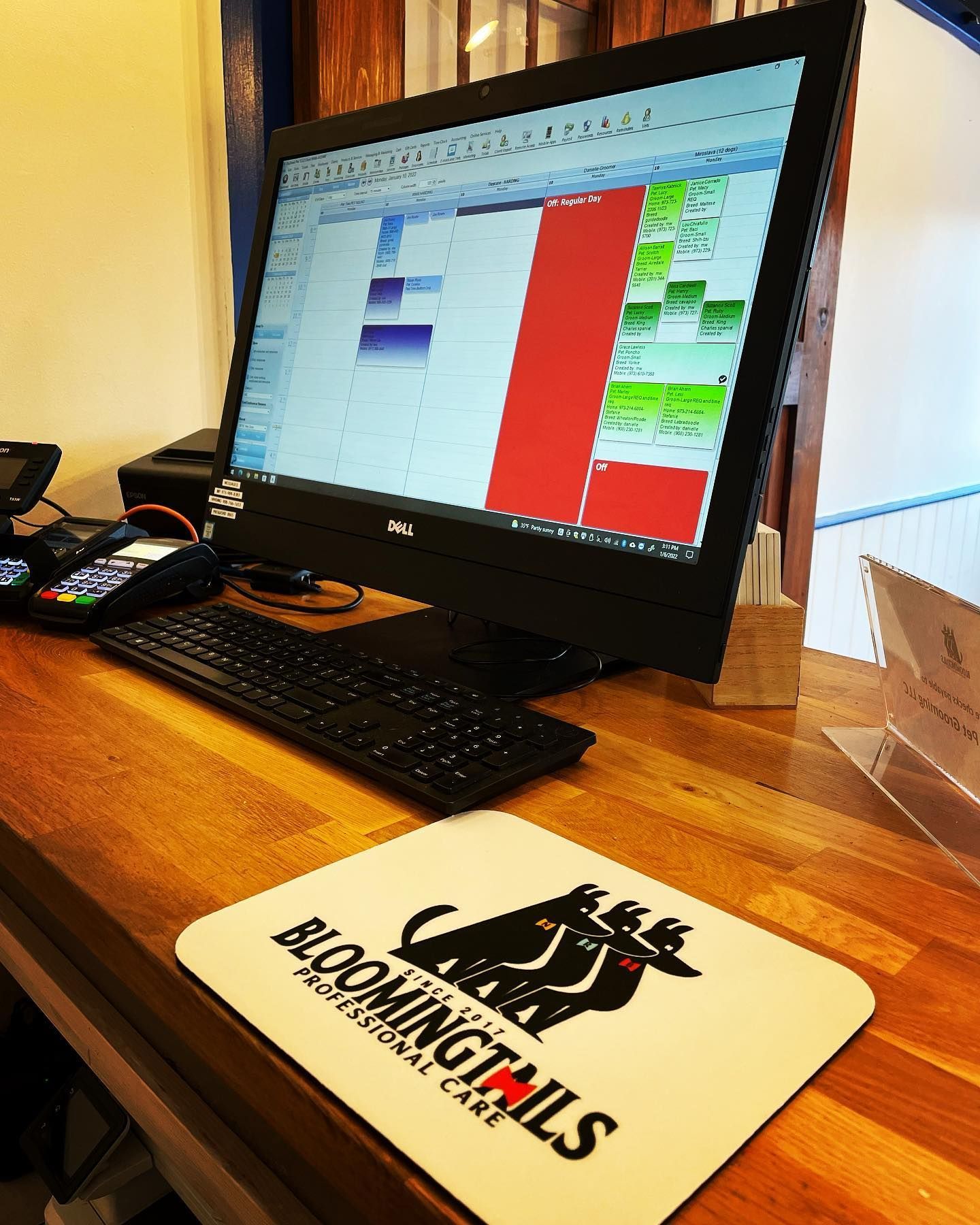 Laptop on a wooden desk displaying a colorful schedule, with a booking tools mousepad in front