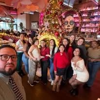 A group of people posing for a photo in a decorated restaurant, with a person in the foreground taking a selfie.