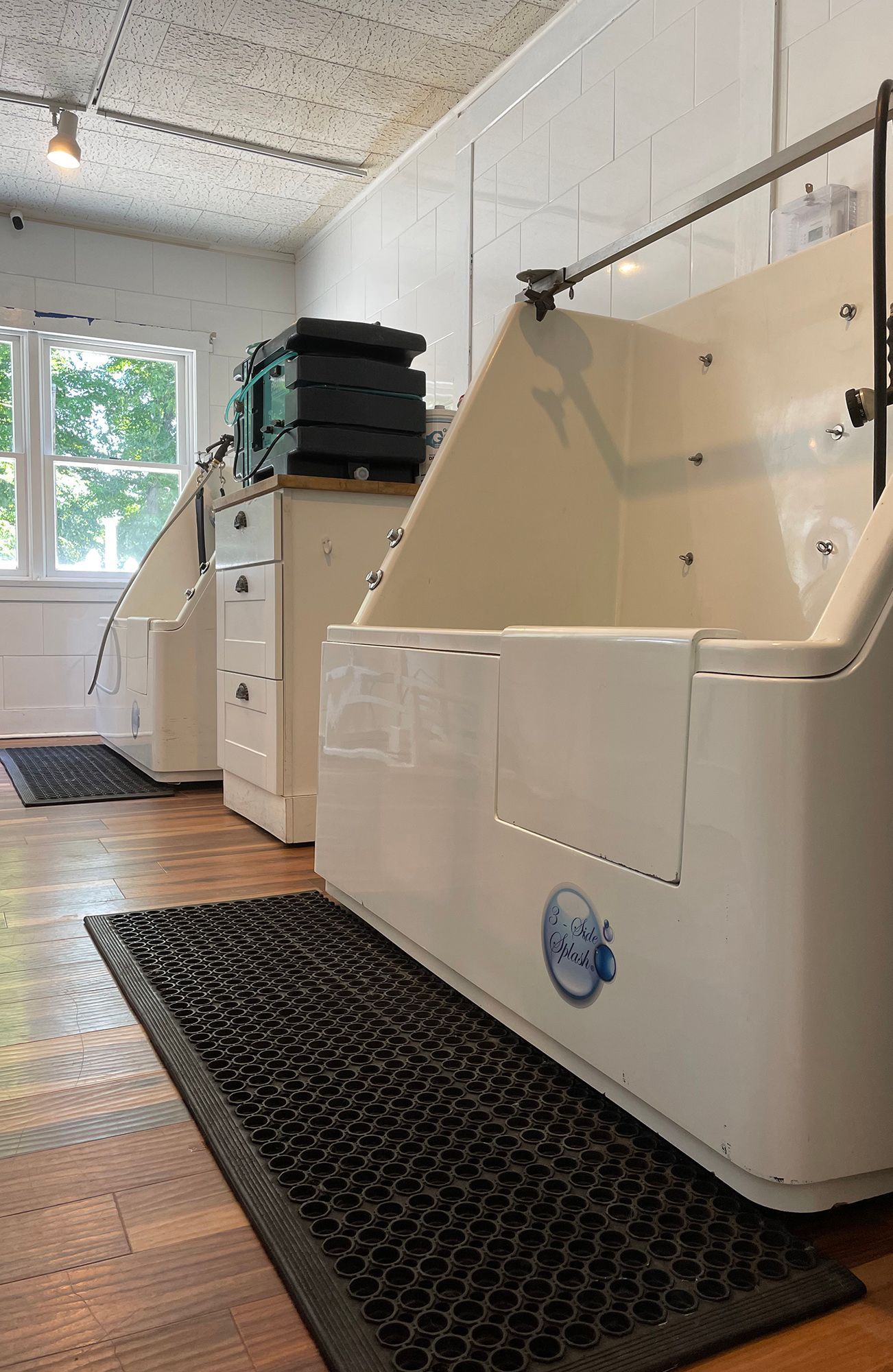 Laundry room with white washing machines and a utility sink on black floor mats