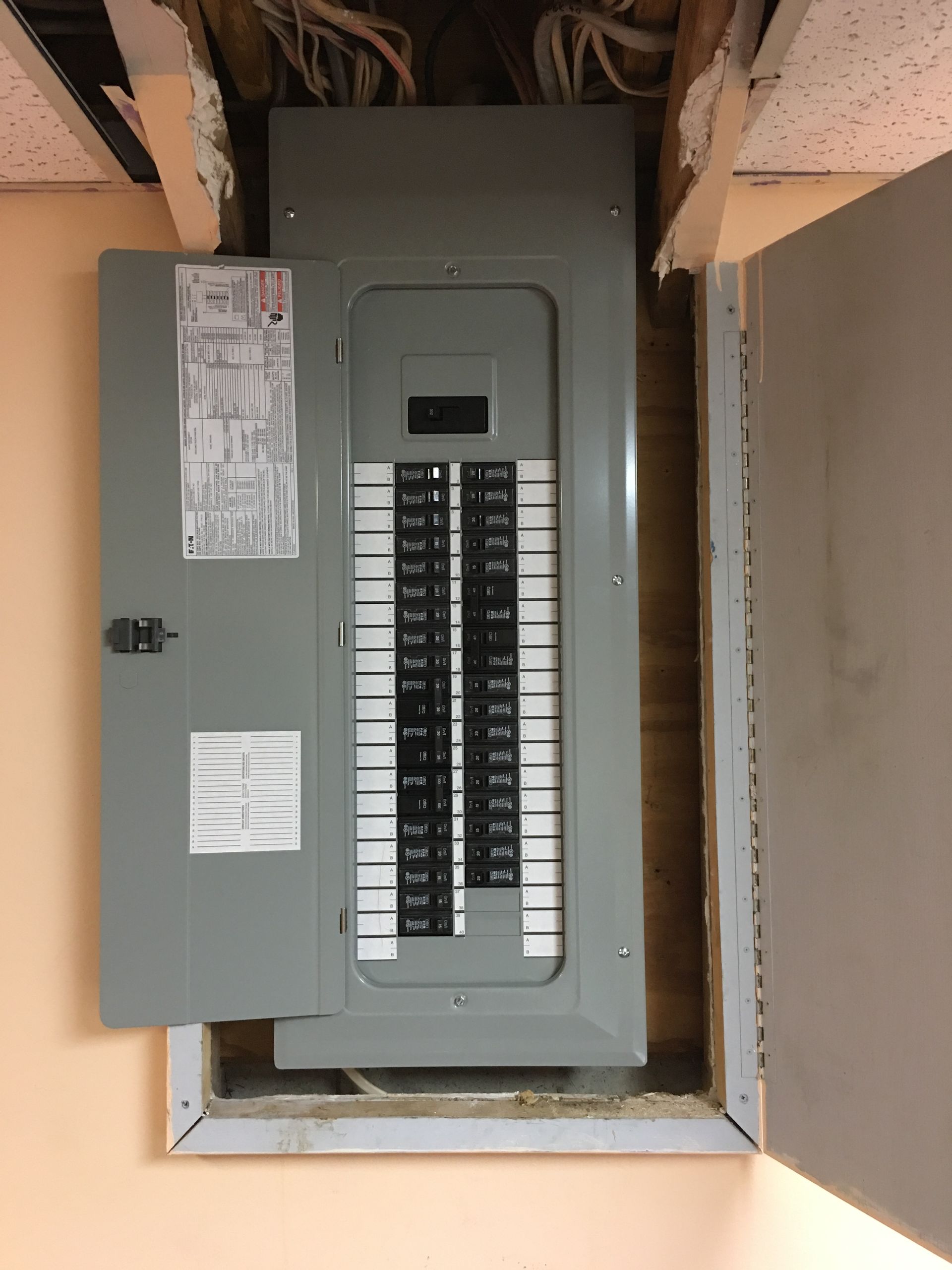 Open electrical breaker panel with labels and circuit switches in a wall recess